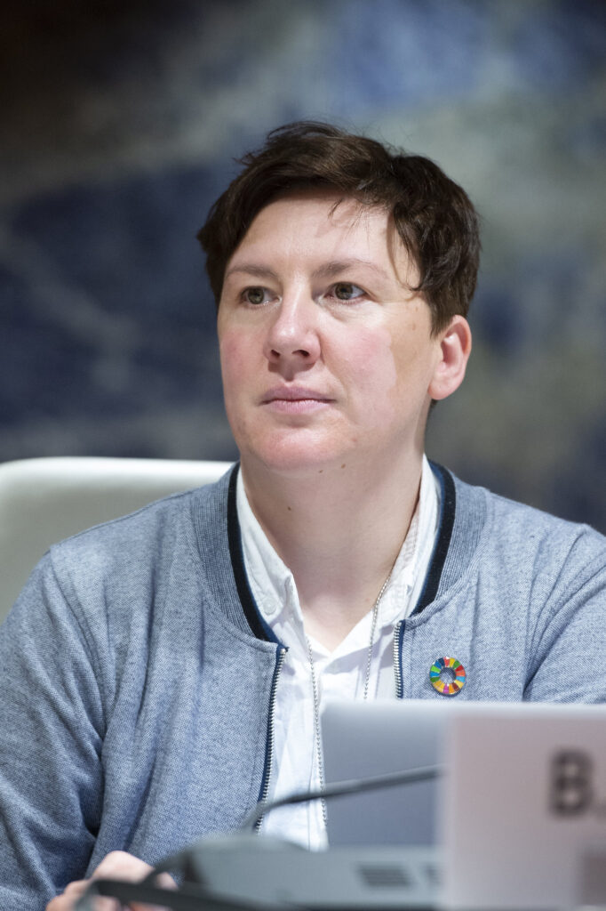 Biljana Ginova, a woman with short cropped hair and a grey jacket, looks up.