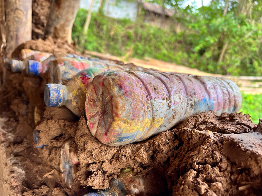 Stacks of stuffed plastic bottles in mud make up a wall