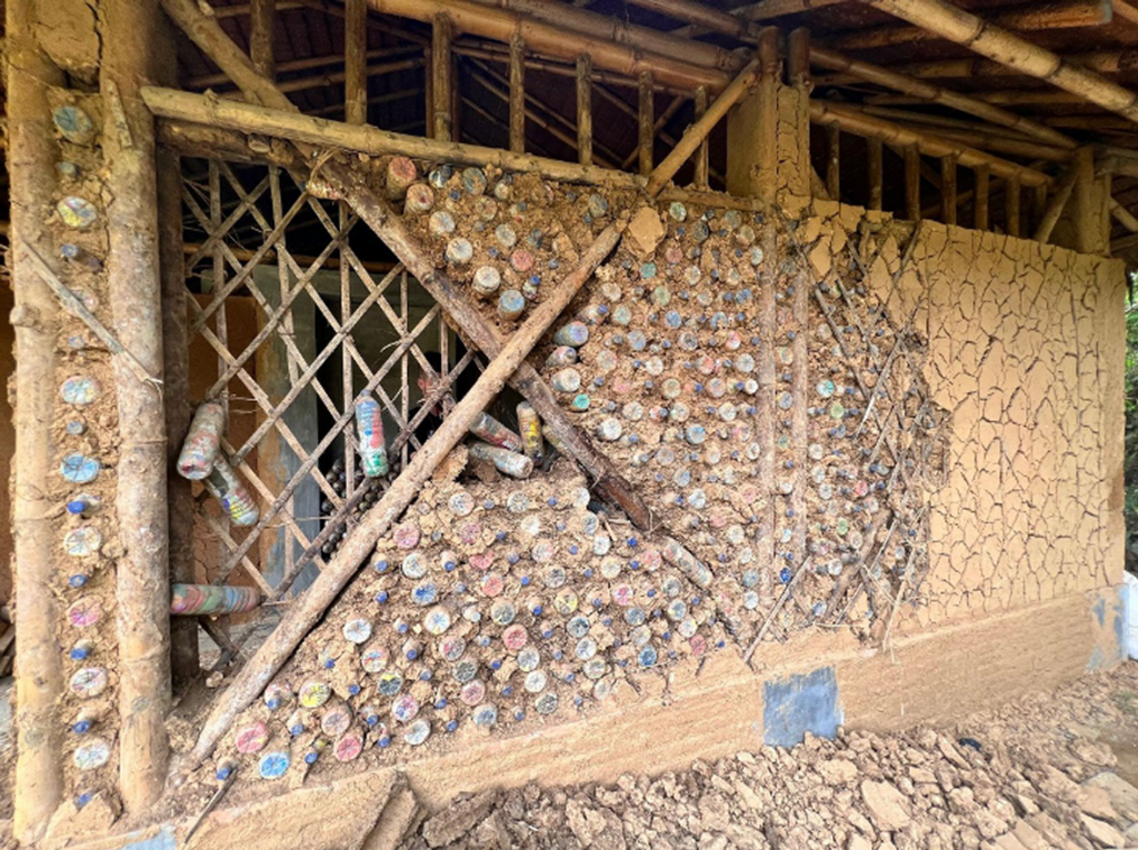 A partially exposed wall shows muddy plastic Ecobricks.