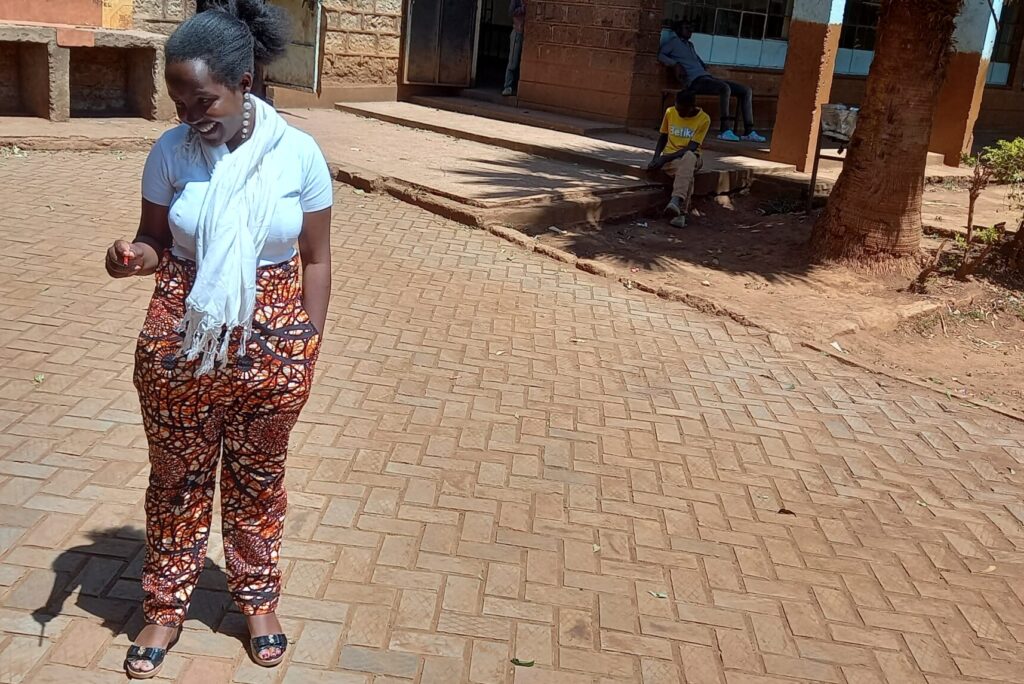 Juliet Gikunda looks down at bricks that have been recycled from plastic, paving the courtyard of the children's home she works at.