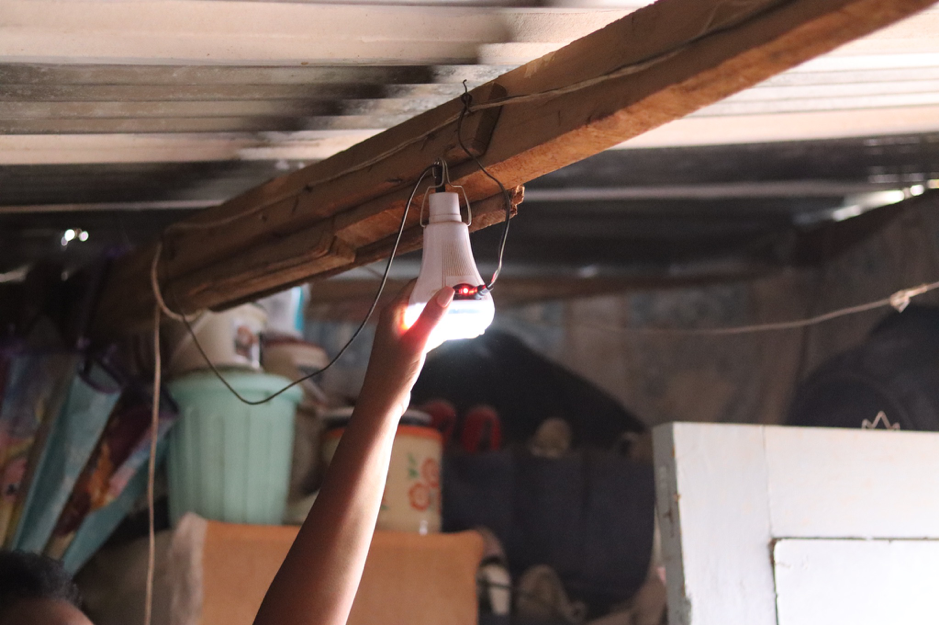 An arm reaches overhead to turn on electricity derived from a solar panel