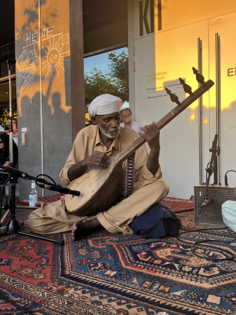 Musician Doshambay playing the Damboora on the stage in Düsseldorf