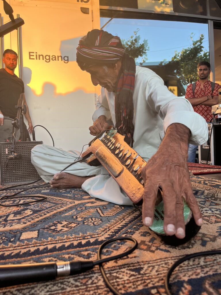 A man plays a traditional Pakistani instrument on a improvised stage