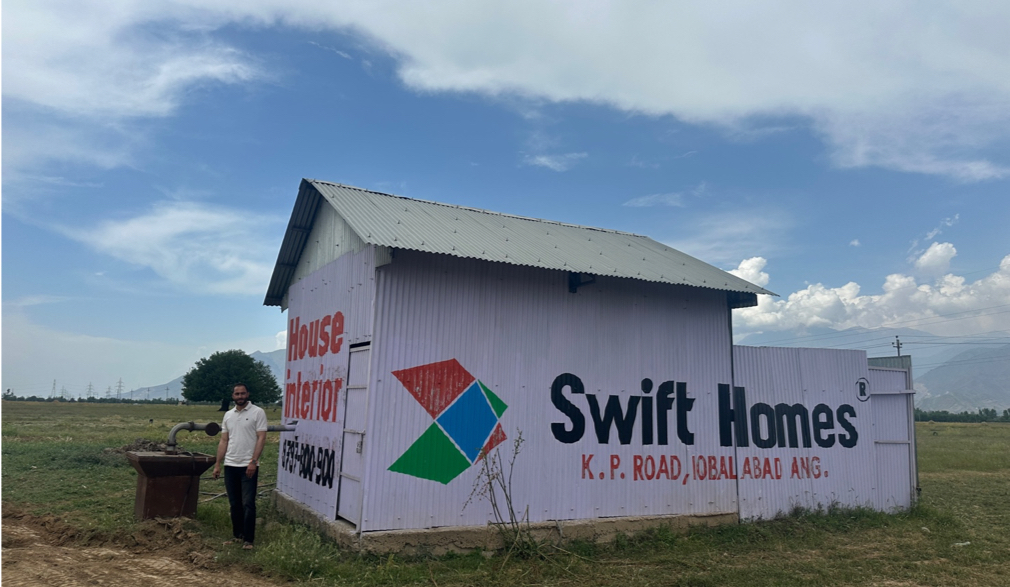 A man stands next to a locked well inside of a house in Kashmir.